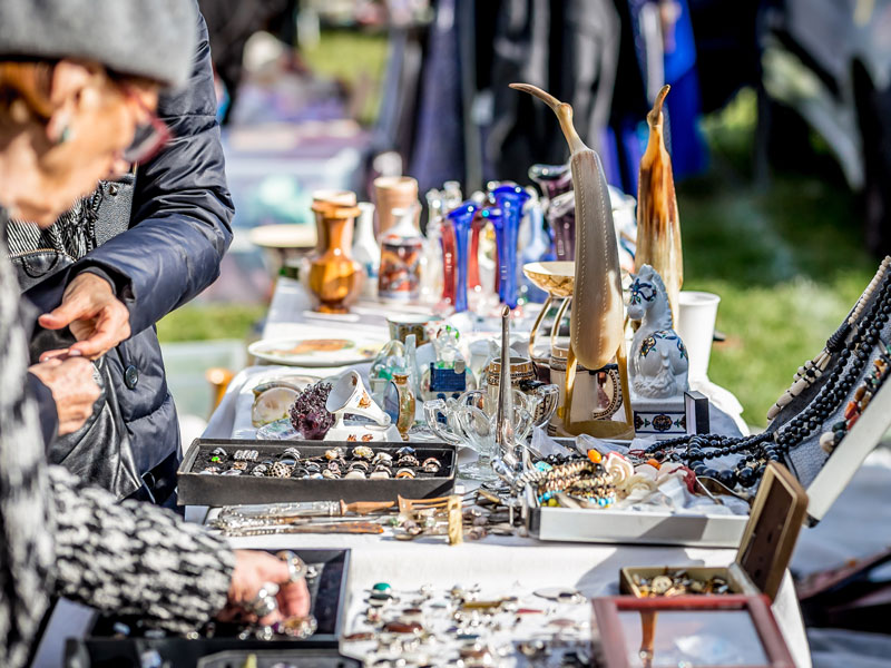 A woman browsing curios on a table at a yard sale.